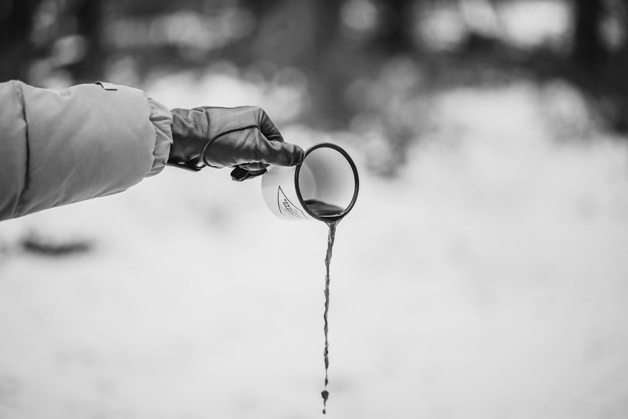 An arm spilling coffee onto the ground from a white cup