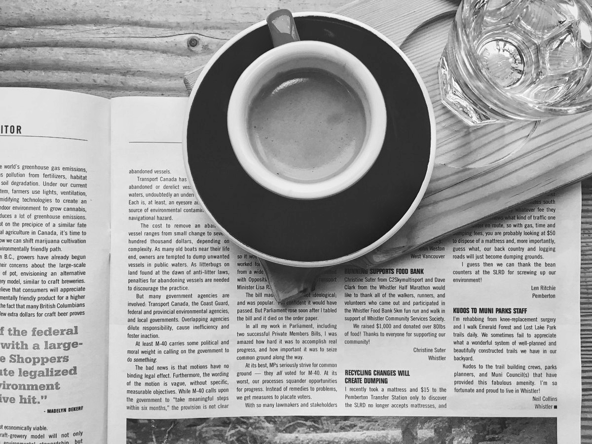 An espresso cup sits atop a newspaper, seen from above.