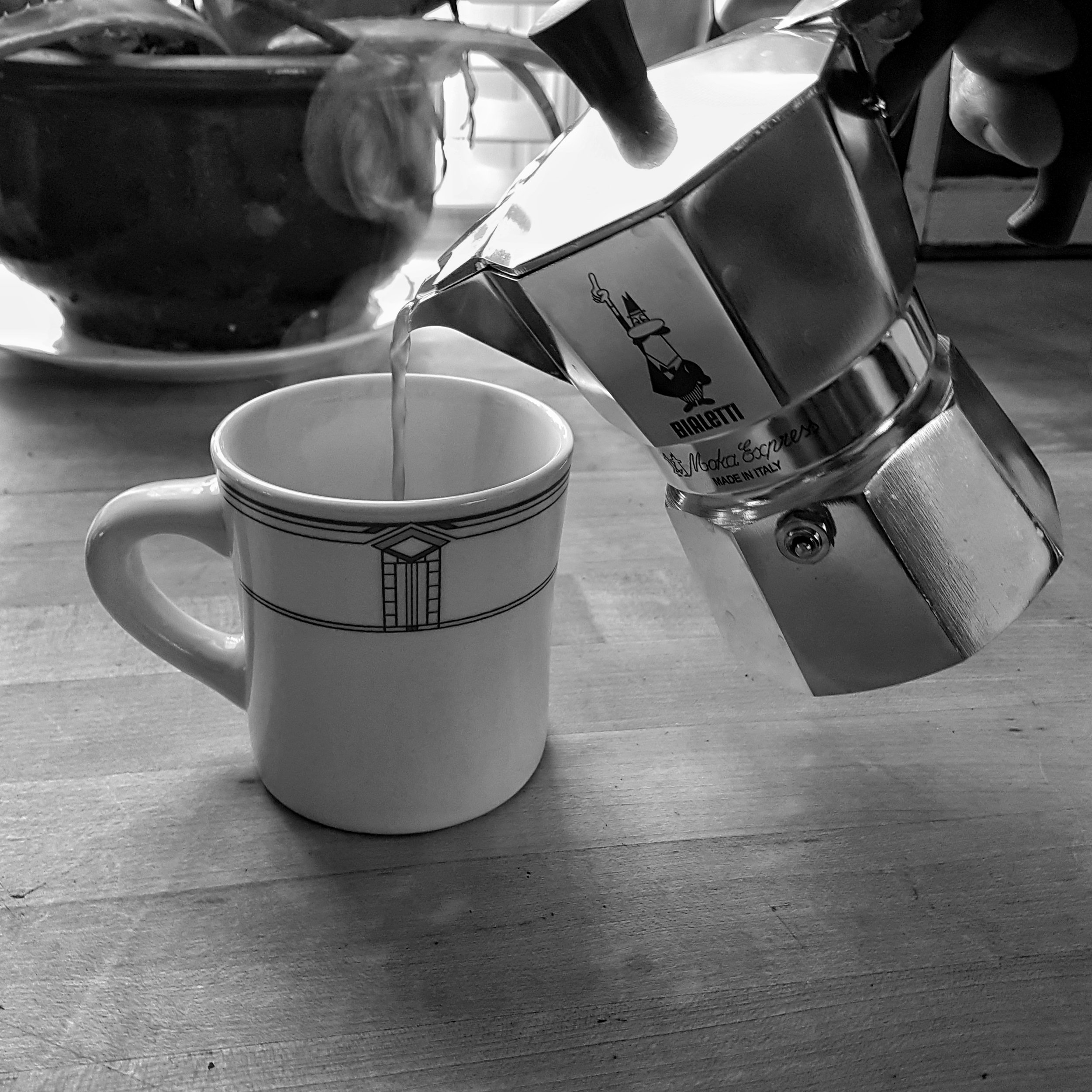 A Moka Pot pouring coffee into a cup on a table