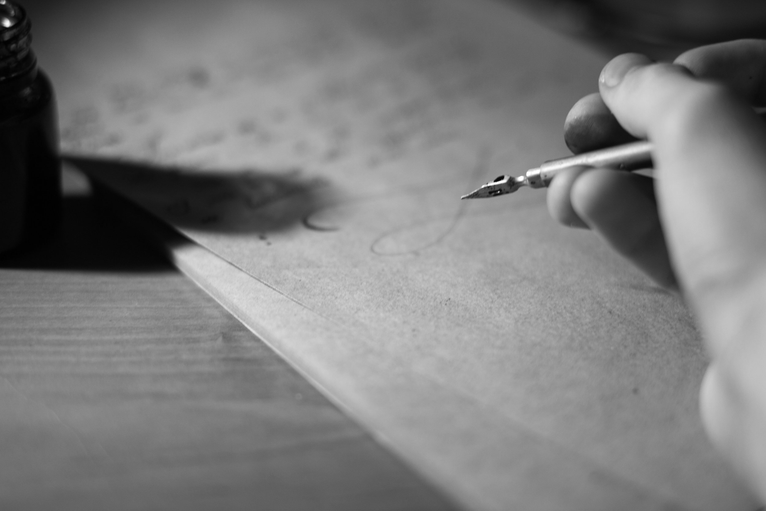 A hand holding a pen above a sheet of paper