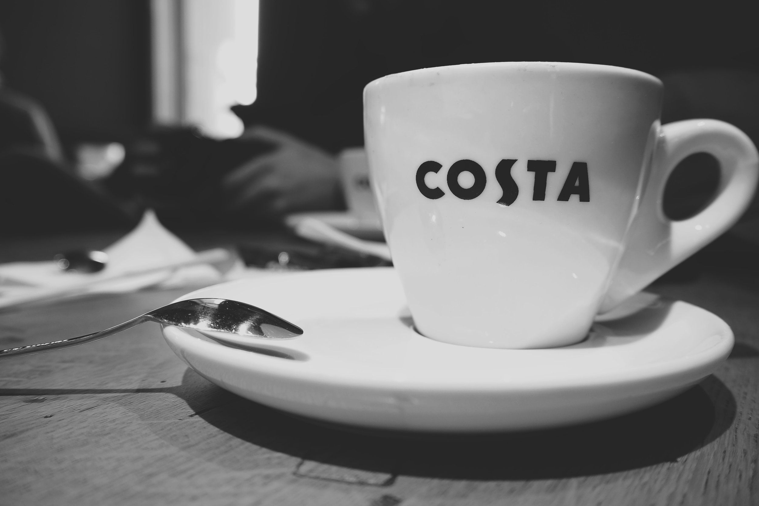 A Costa coffee cup sits on a table