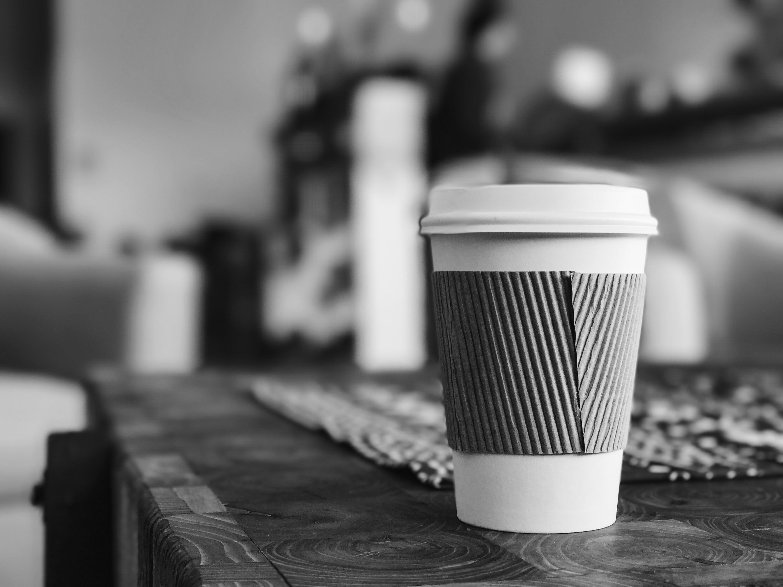 A takeaway coffee cup sits on a wooden table