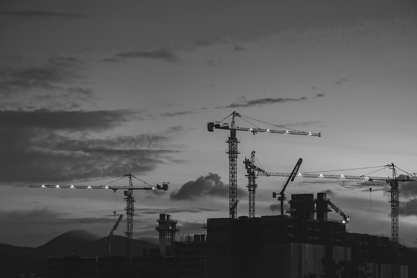 Cranes against a skyline at sunset