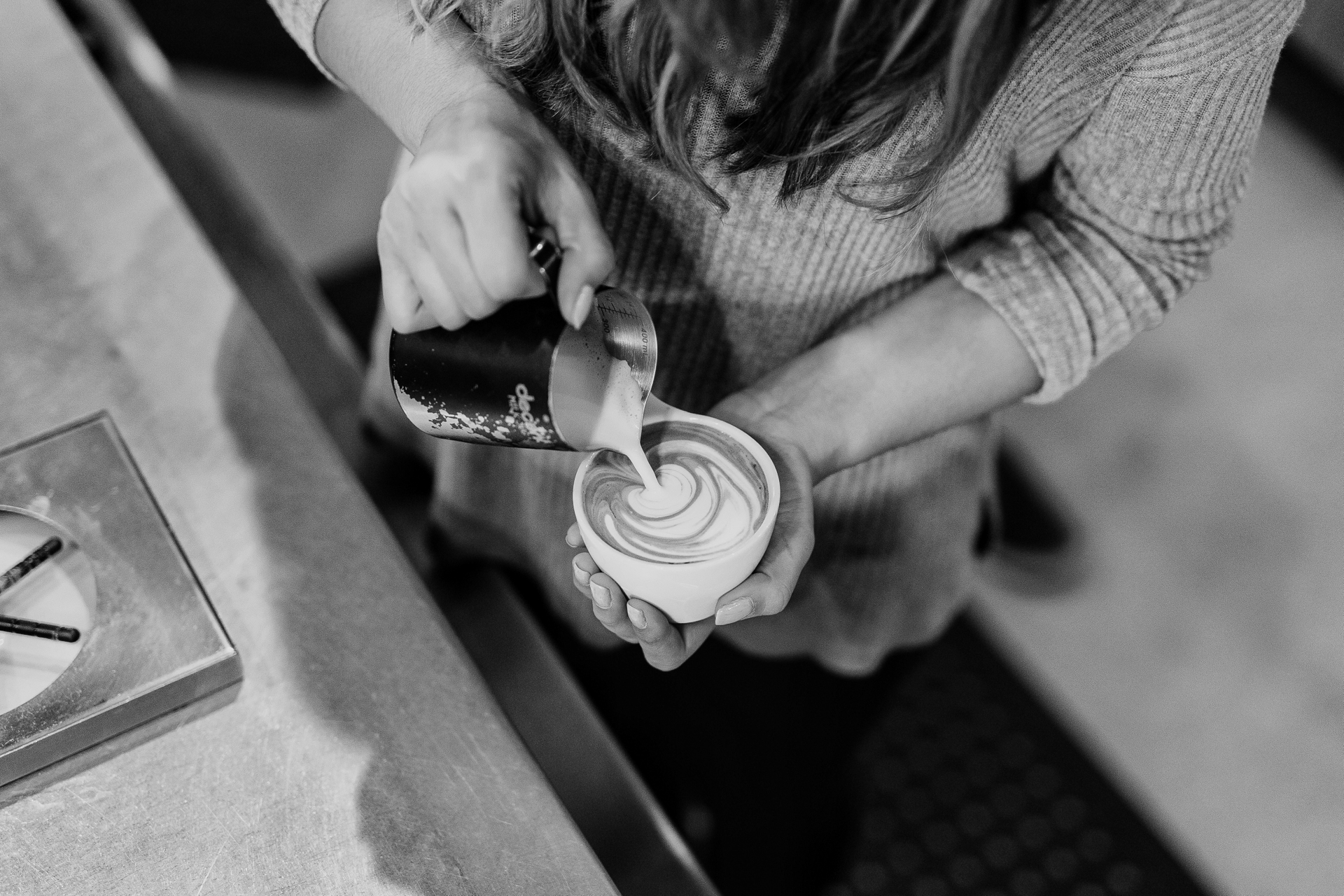 A barista pours a latte, seen from above