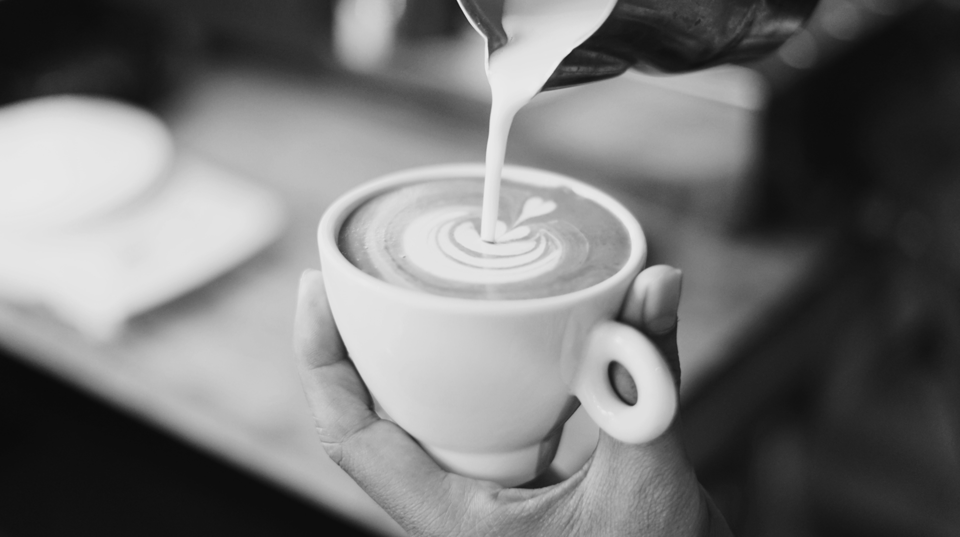 A barista pours latte art into a cup