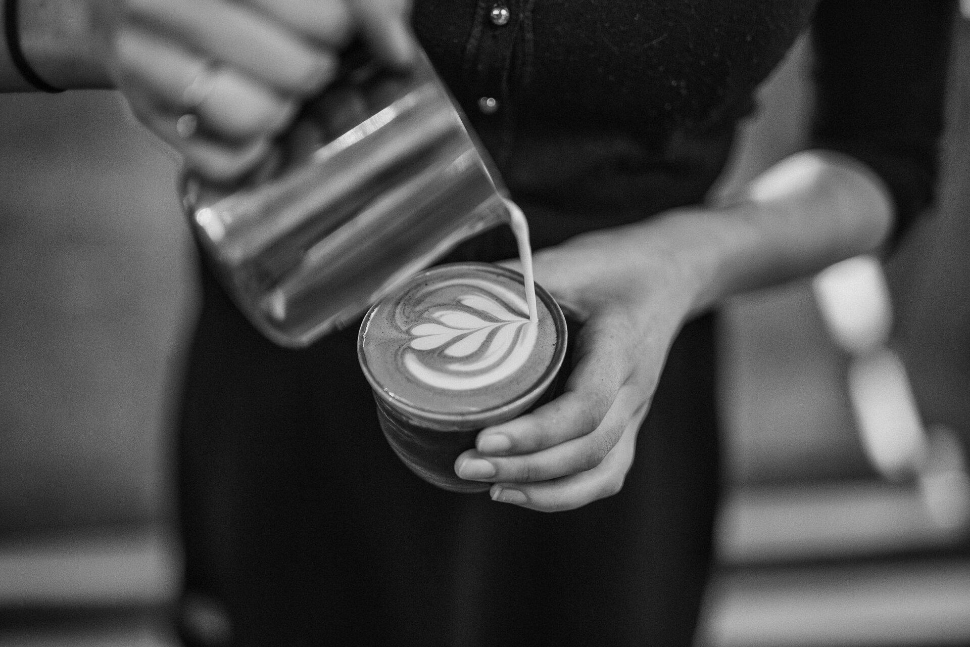 A barista pouring latte art, seen from above.