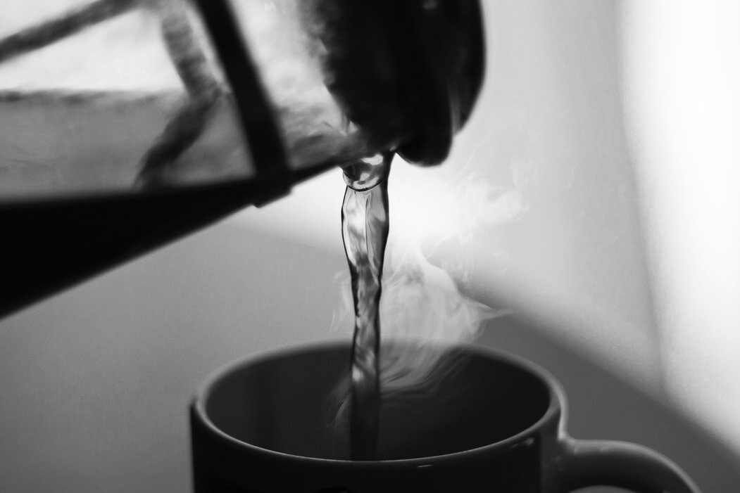 Close up of a French press pouring coffee into a mug.