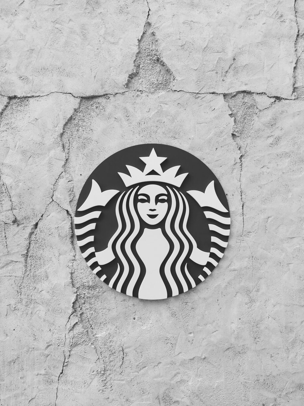 A Starbucks sign hangs on a rock wall.