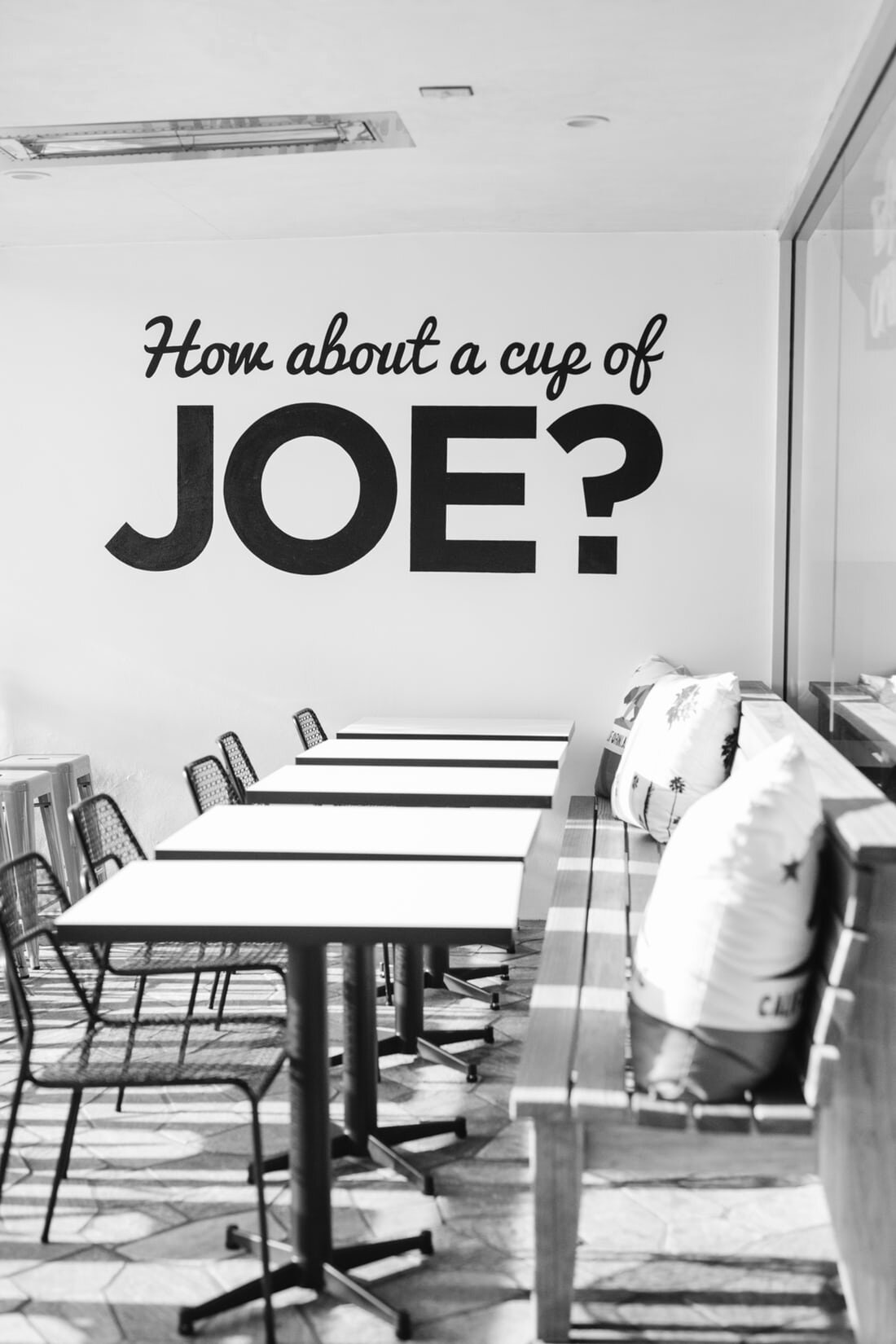 An empty coffee shop with the words “how about a cup of joe?” painted on the walls