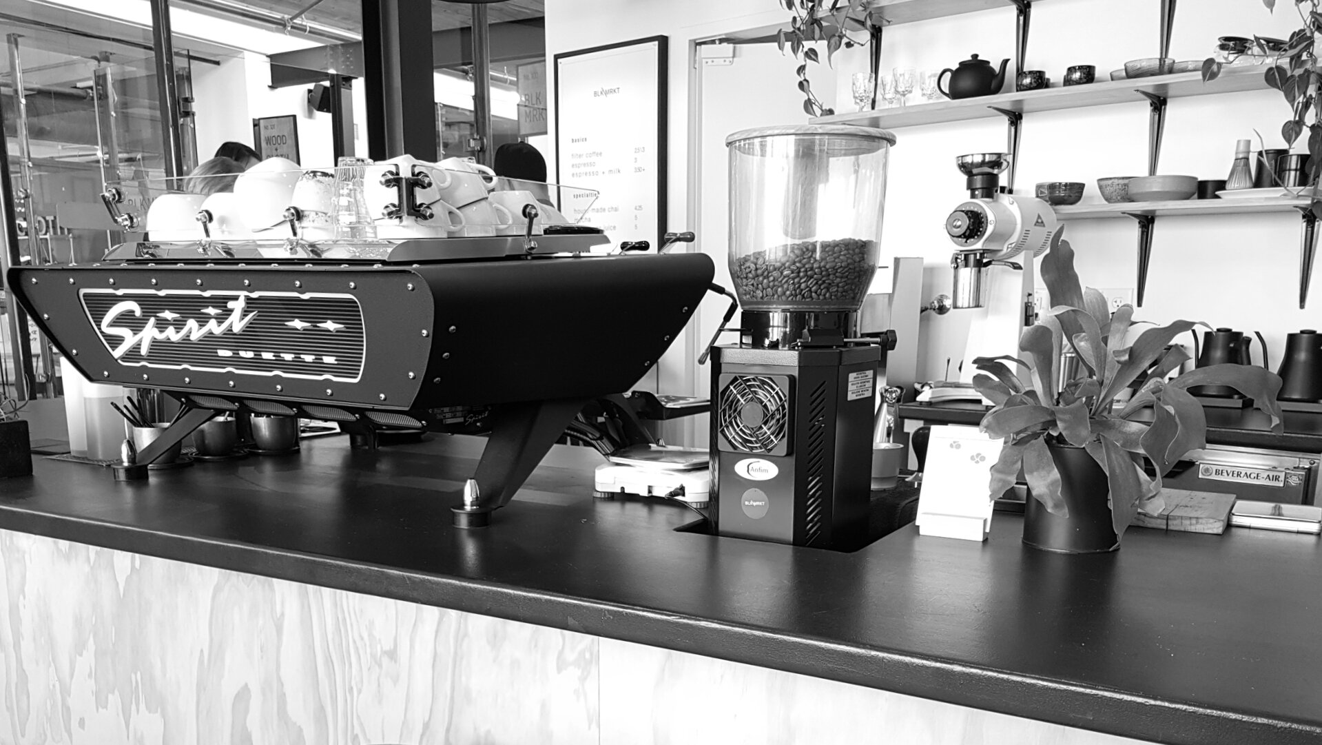 A shot of Blk\Mrkt’s cafe in Traverse City, featuring an espresso machine and grinders sitting atop a wooden bar