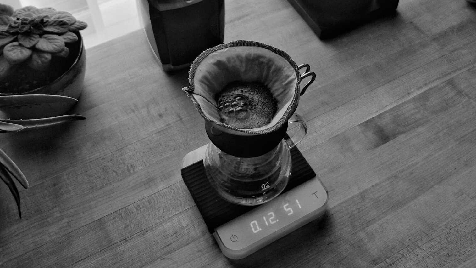 A Hario V60 with a cloth filter sits on a scale filled with brewing coffee.