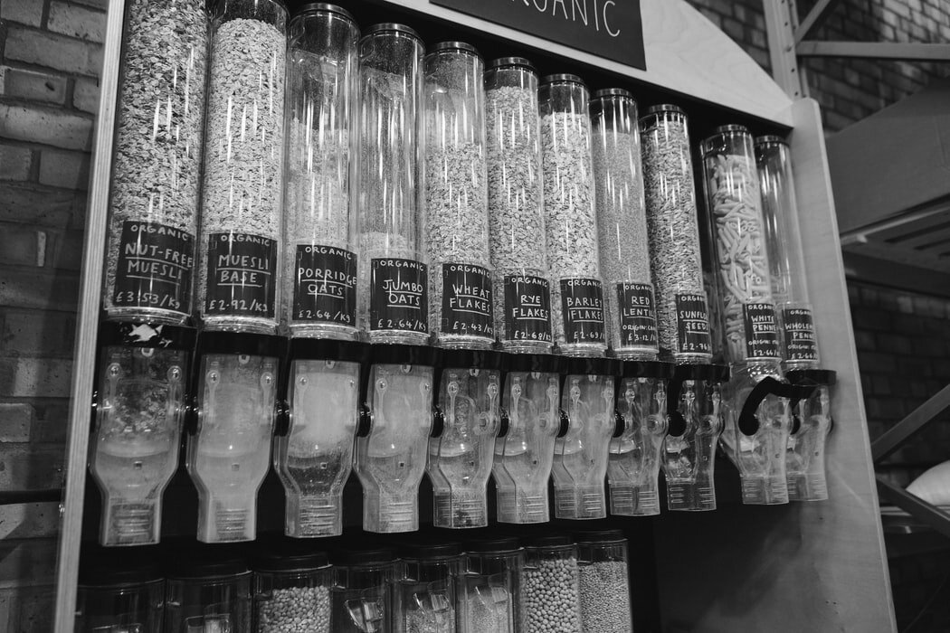 Plastic bulk food dispensers filled with various grains. Via Unsplash