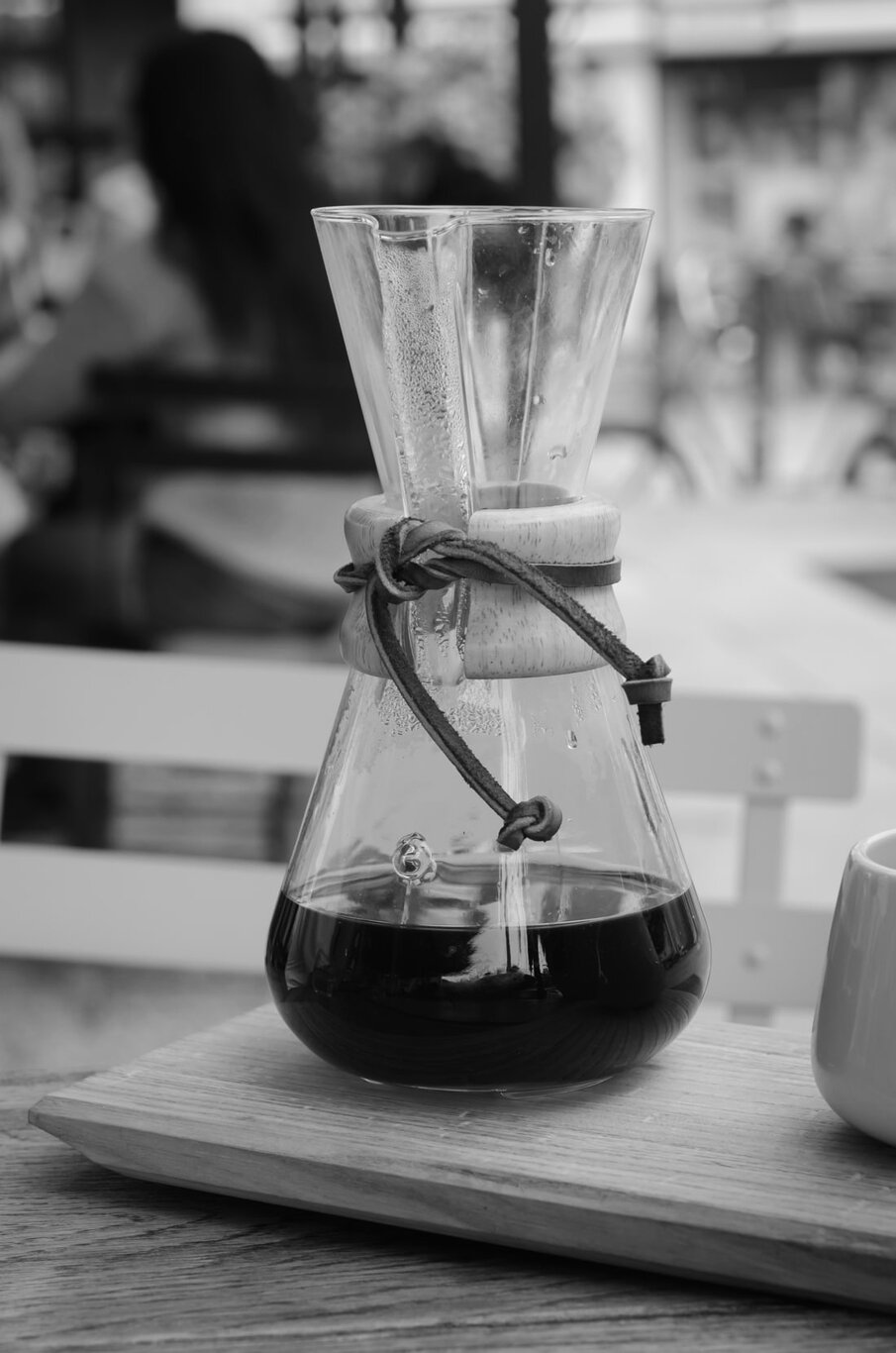 A Chemex coffee brewer full of coffee sits on a wooden tray, ready to be served. Via Unsplash