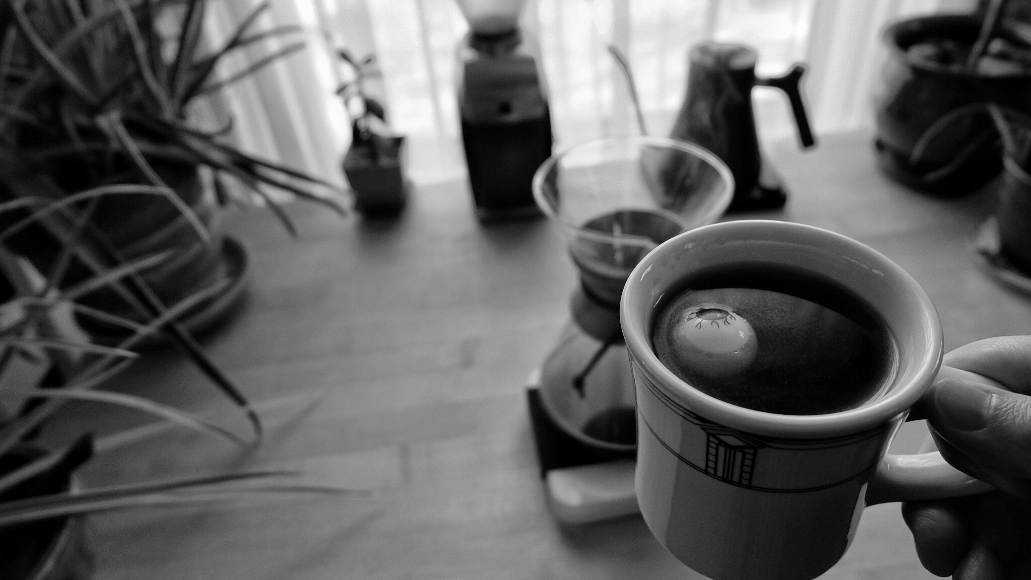 A fake eyeball floats in a cup of coffee held above a brewing station