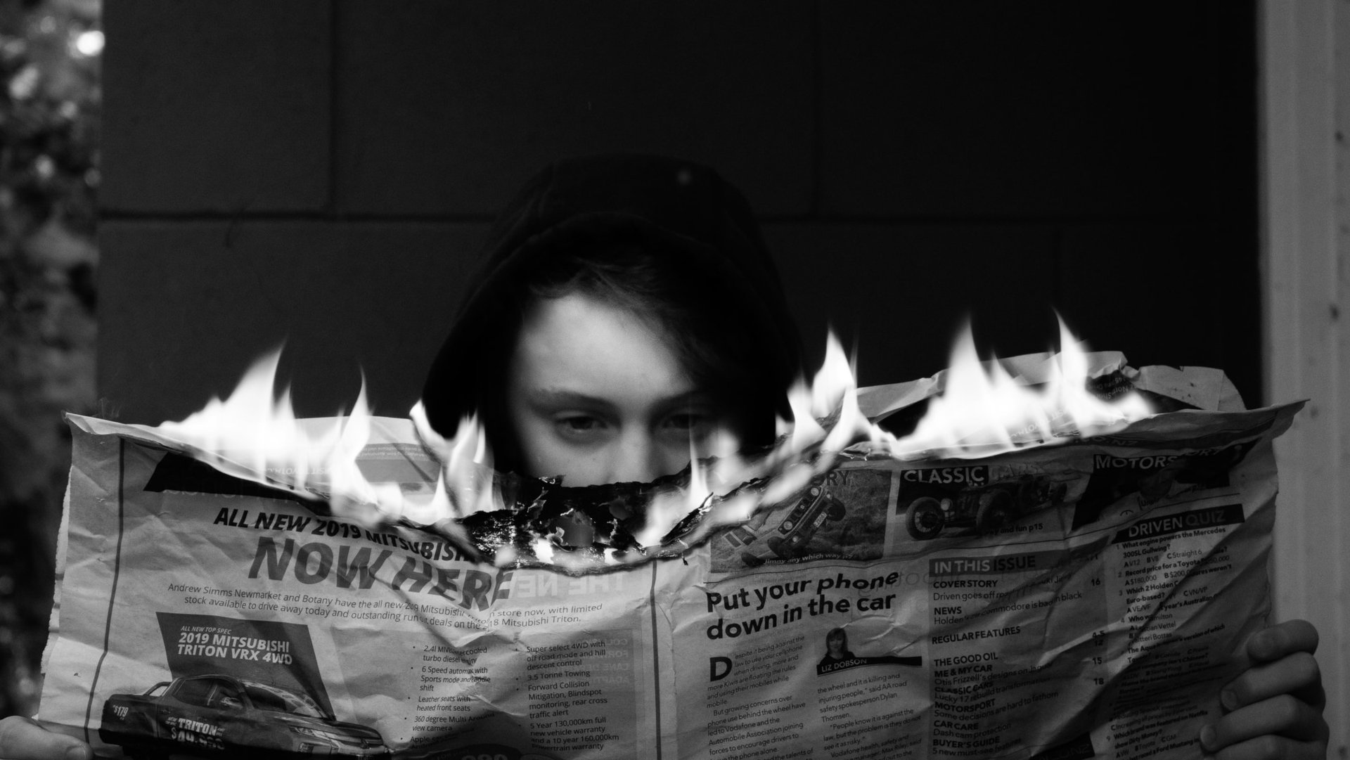 Close up of a person reading a newspaper that is on fire.