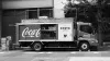 A small Coca-Cola delivery truck, with its sliding back door open, also sporting a Costa Coffee logo