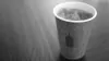 Closeup of a takeaway coffee cup, filled with iced coffee, featuring the Blue Bottle Coffee logo 