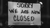 A handwritten sign sellotaped to a window that reads "sorry we are now closed"