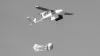 A white delivery drone with zipline written on the side drops a package with a little parachute.